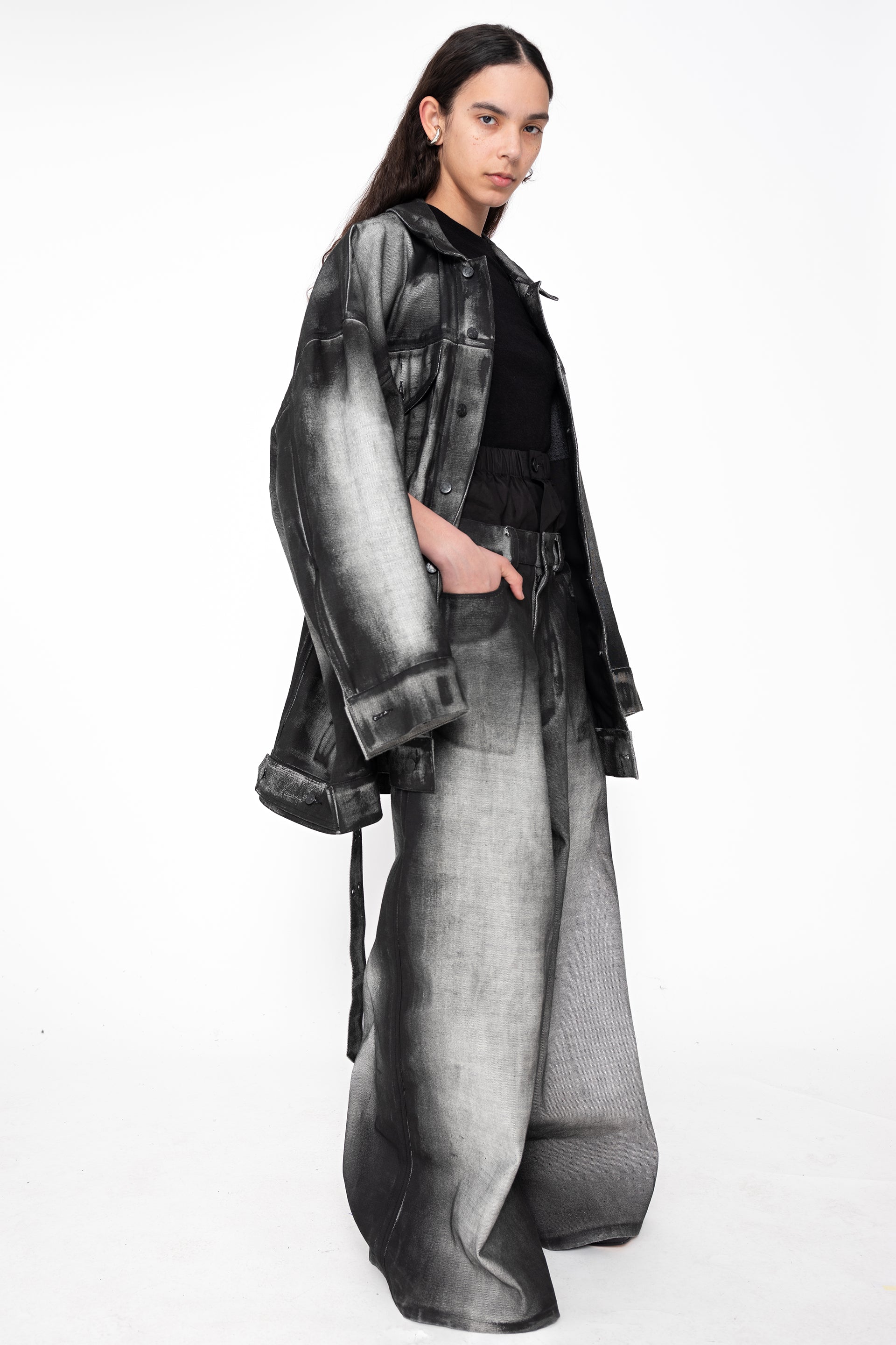 female-wearing-oversized-black-and-gray-spray-painted-denim-set-on-white-background-full-body-three-quarter