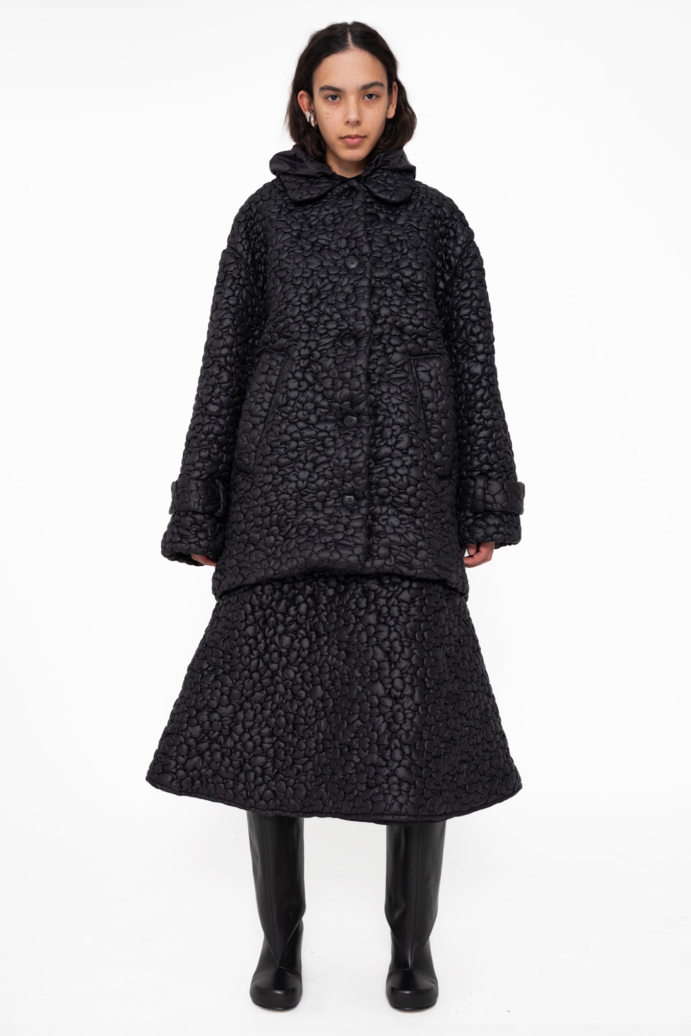 female-wearing-black-quilted-aline-skirt-with-black-quilted-windbreaker-with-flower-embroidery-on-white-background-full-body