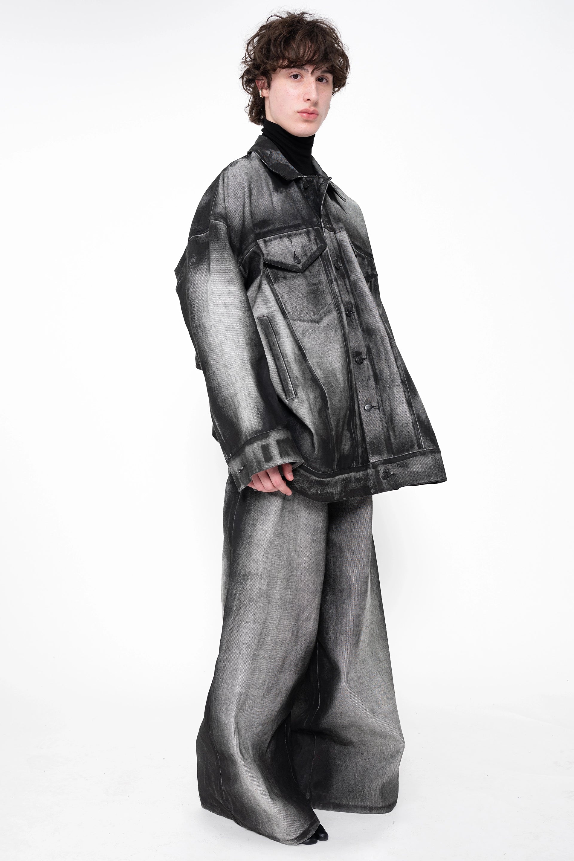 male-wearing-oversized-black-and-gray-spray-painted-denim-set-on-white-background-full-body-three-quarter