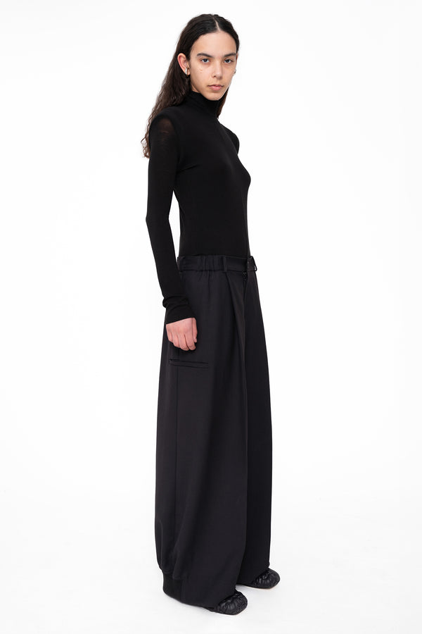 female-wearing-black-tight-turtleneck-with-tailored-wide-leg-suit-pants-on-white-background-full-body-three-quarter