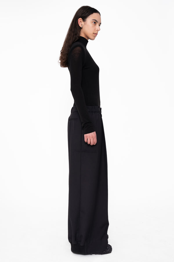 female-wearing-black-tight-turtleneck-with-tailored-wide-leg-suit-pants-on-white-background-full-body-side