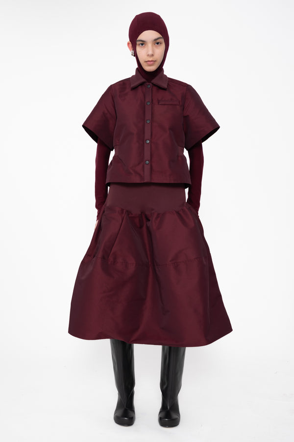 female-wearing-cropped-bordeaux-bomber-shirt-with-midi-skirt-in-same-bordeaux-color-with-bordeaux-balaclava-turtleneck-on-white-background-full-body-front