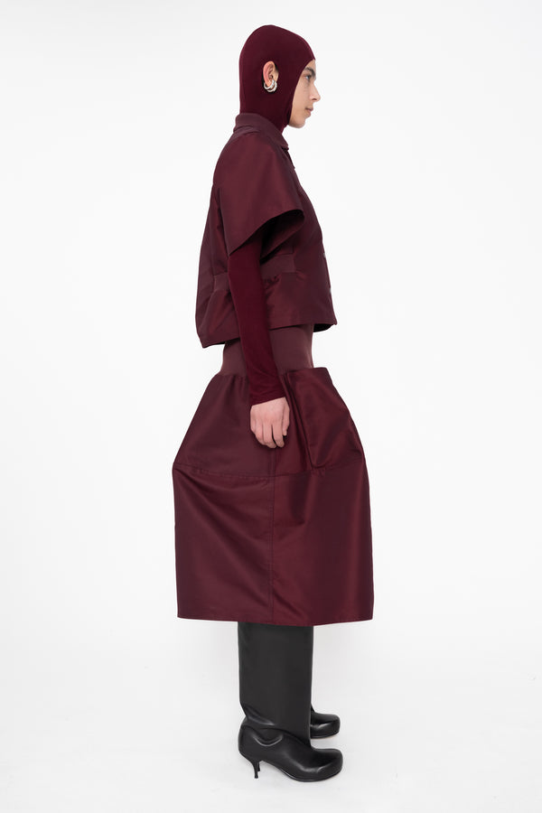 female-wearing-cropped-bordeaux-bomber-shirt-with-midi-skirt-in-same-bordeaux-color-with-bordeaux-balaclava-turtleneck-on-white-background-full-body-side