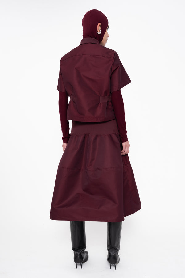 female-wearing-cropped-bordeaux-bomber-shirt-with-midi-skirt-in-same-bordeaux-color-with-bordeaux-balaclava-turtleneck-on-white-background-full-body-back-side