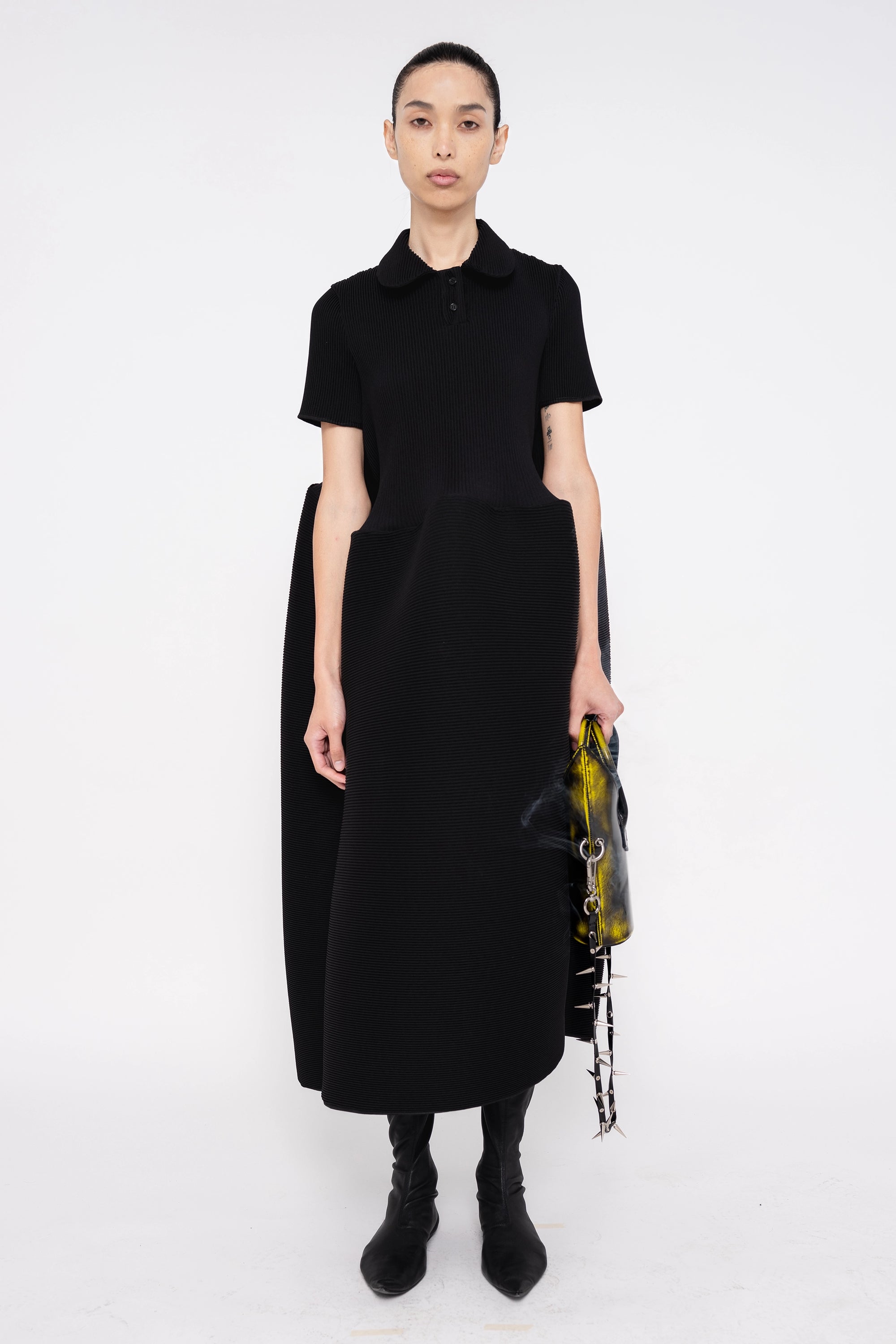 female-wearing-black-pleated-dress-with-polo-collar-and-ruffled-skirt-on-white-background-full-body-front