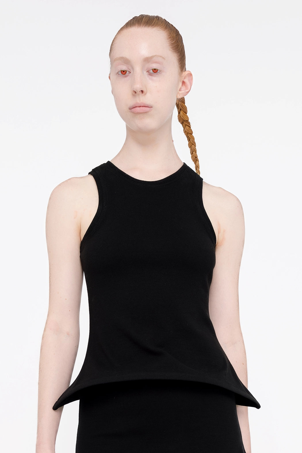 female-wearing-black-tank-top-with-pointy-hem-on-white-background-torso-close-up-front